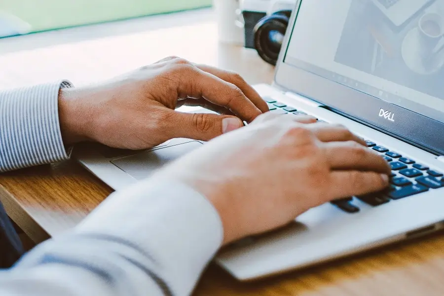 Bild eines Notebooks auf dem zwei Hände liegen und tippen